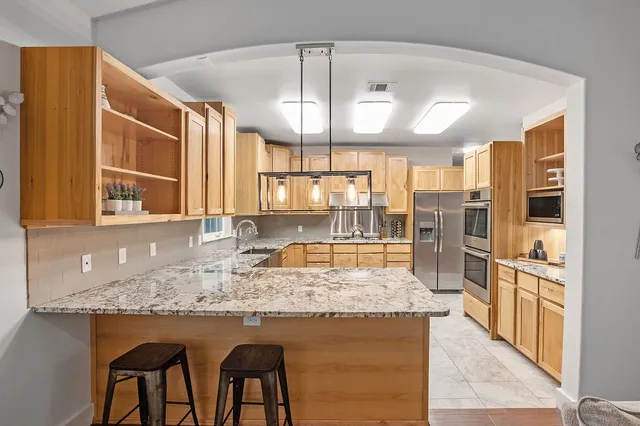 a kitchen with kitchen island granite countertop wooden floor and a refrigerator