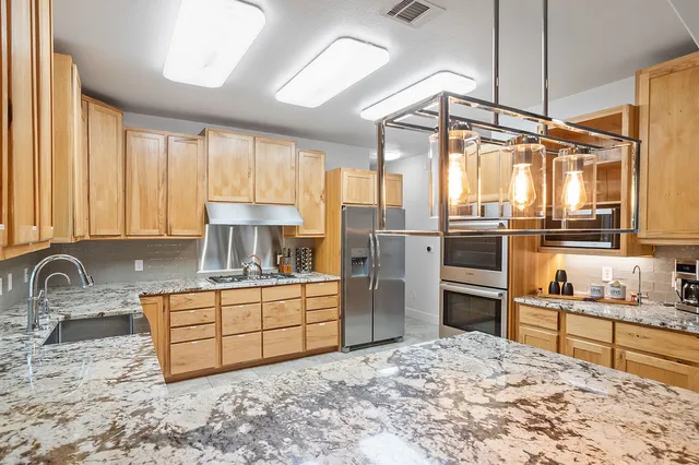 a kitchen with stainless steel appliances kitchen island granite countertop a refrigerator and cabinets