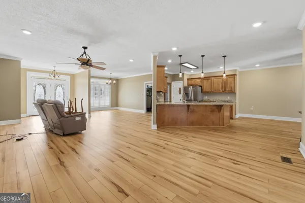 a view of empty room with wooden floor and fan