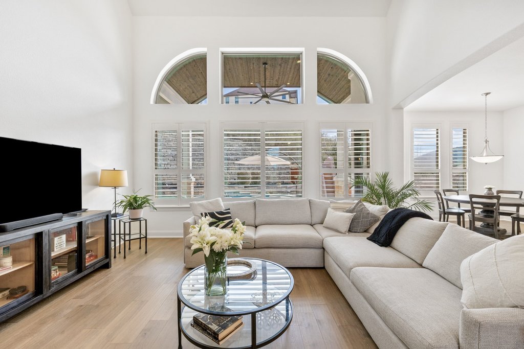 5812 Davenport Divide Road Austin, TX 78738 - Photo 7 of 40 Natural light pours through arched windows and plantation shutters, connecting the living space to the backyard beyond.