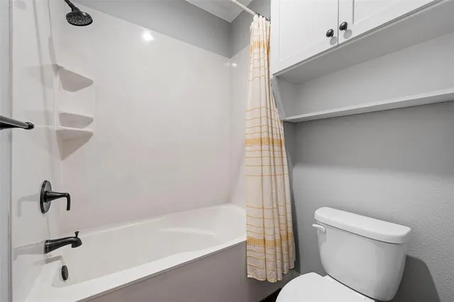 a white toilet sitting next to a bath tub