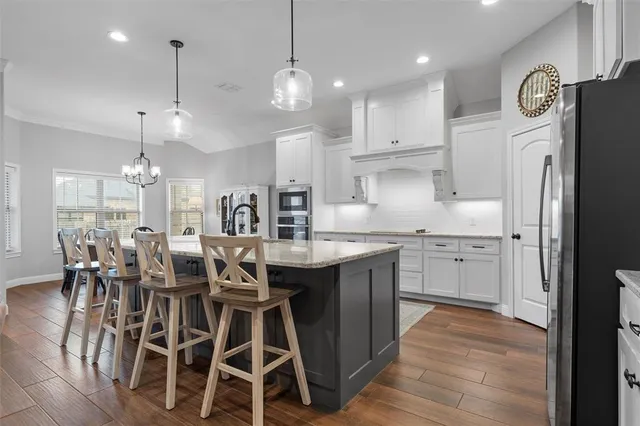a kitchen with stainless steel appliances kitchen island granite countertop a dining table chairs and white cabinets