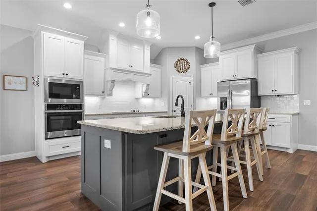 a kitchen with stainless steel appliances kitchen island granite countertop a table chairs sink and cabinets