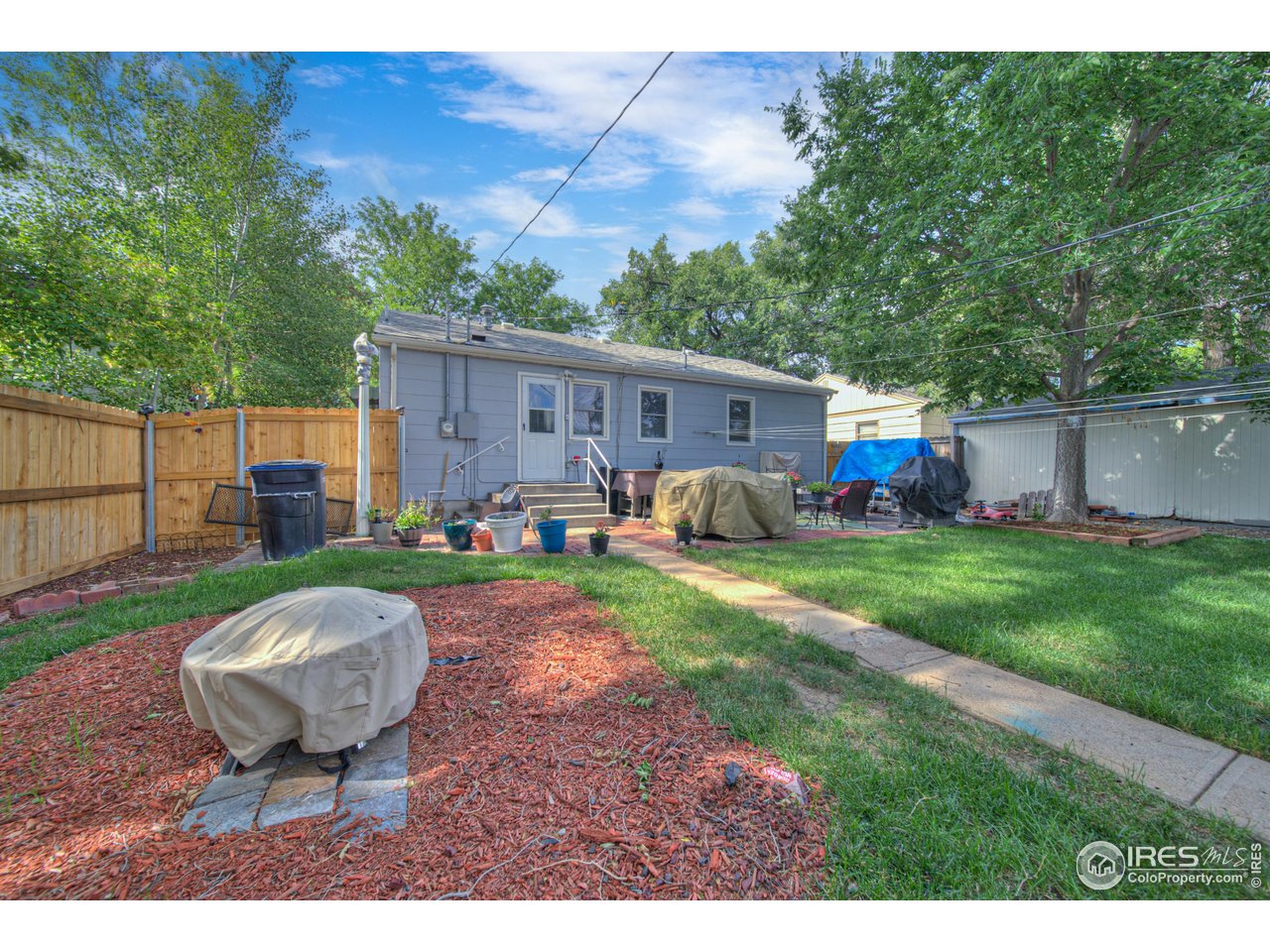714 Delmar Street Sterling, CO 80751 - Photo 20 of 22 a view of a backyard with table and chairs potted plants and a palm tree
