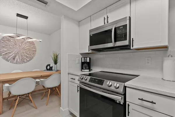 a kitchen with stainless steel appliances a stove a microwave a sink and white cabinets