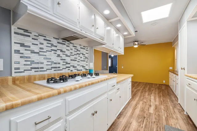 a large kitchen with kitchen island a island a sink dishwasher a dining table and chairs with wooden floor