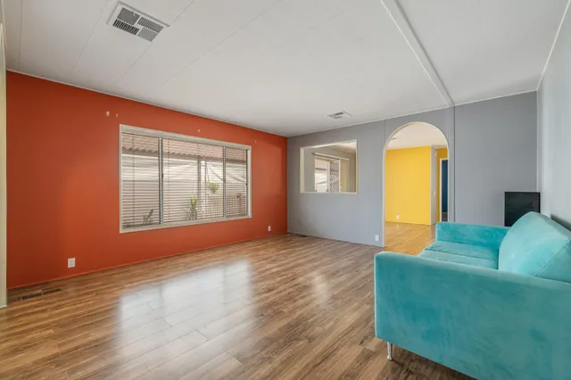 a view of a hallway with wooden floor and a living room