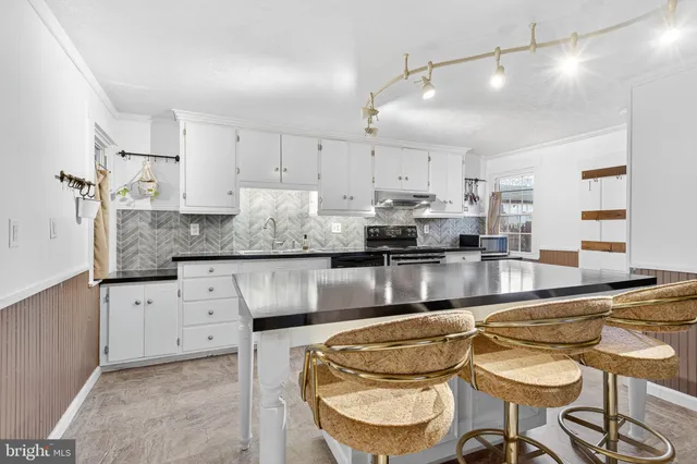 a kitchen with granite countertop a sink and white cabinets