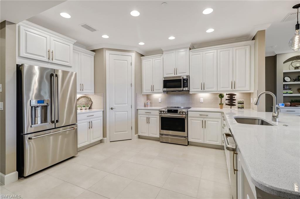9653 Montelanico Loop, Unit 102 Naples, FL 34119 - Photo 4 of 26 a kitchen with stainless steel appliances granite countertop a refrigerator sink and microwave