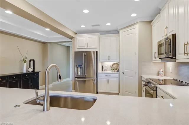a kitchen with kitchen island a counter top space a sink stainless steel appliances and cabinets