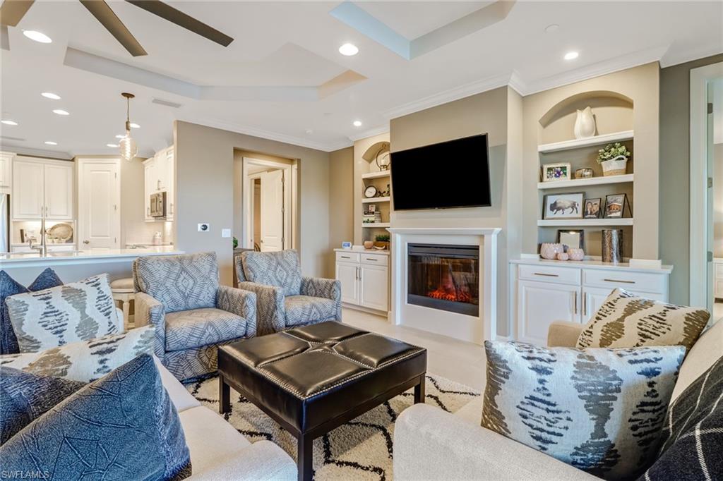 9653 Montelanico Loop, Unit 102 Naples, FL 34119 - Photo 9 of 26 a living room with furniture a flat screen tv and a fireplace
