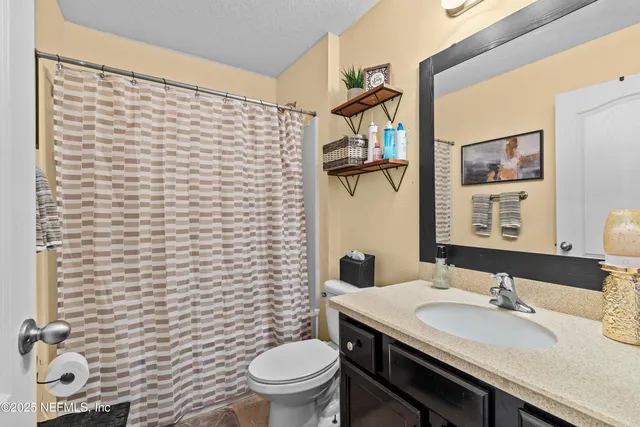 a bathroom with a sink a toilet and shower curtain