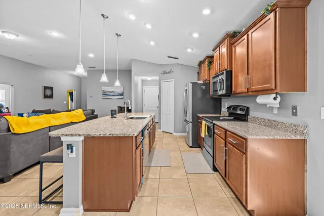 a kitchen with kitchen island granite countertop a sink a counter top space and stainless steel appliances