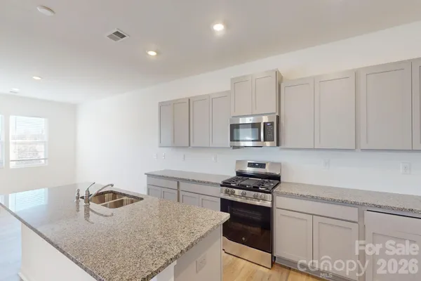 a kitchen with granite countertop a sink stove and cabinets