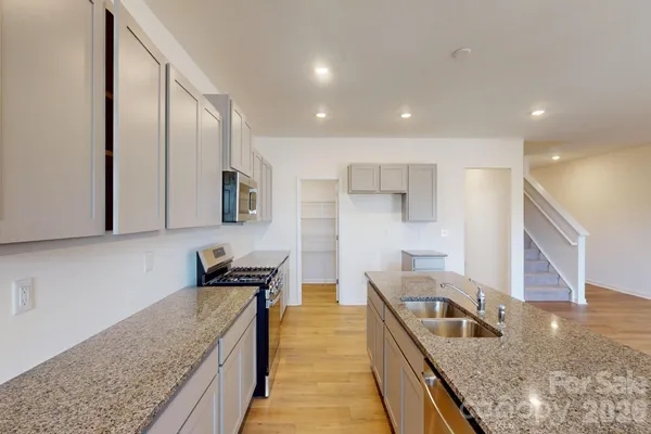 a kitchen with stainless steel appliances granite countertop sink stove and refrigerator