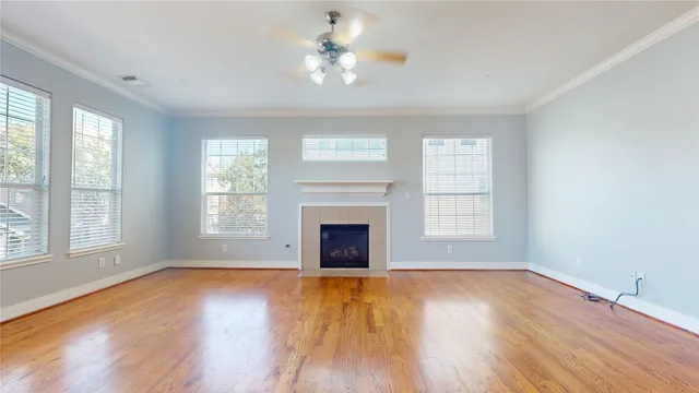 an empty room with windows fireplace and wooden floor