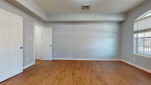 an empty room with wooden floor and windows