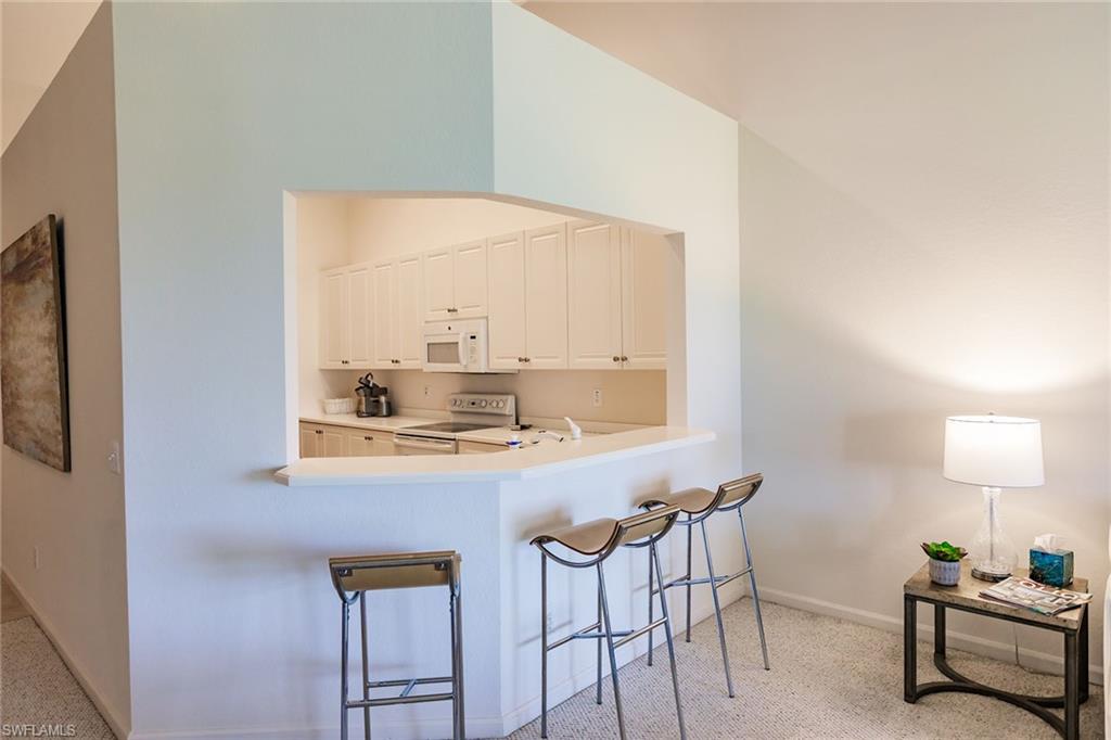 3940 Deer Crossing Court, Unit 4203 Naples, FL 34114 - Photo 15 of 46 a room with a table chairs and a lamp