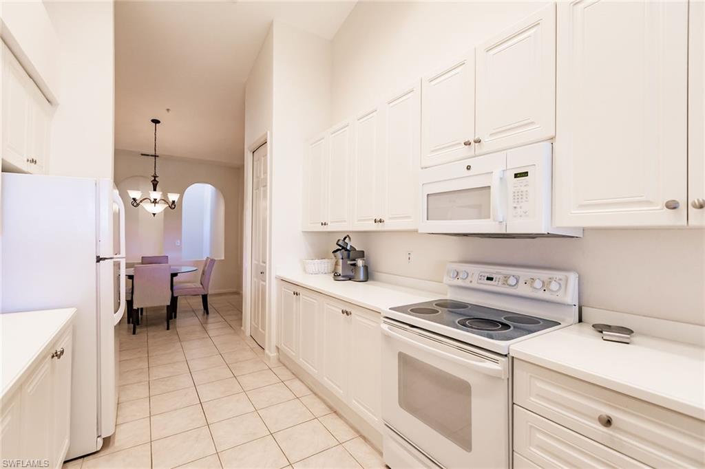 3940 Deer Crossing Court, Unit 4203 Naples, FL 34114 - Photo 22 of 46 a kitchen with white cabinets and white appliances