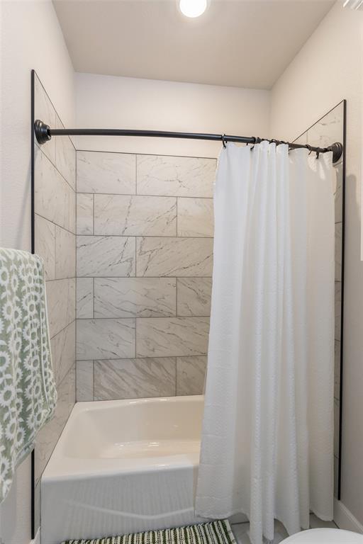 107 Kleingrass Road Abilene, TX 79606 - Photo 25 of 33 Bathtub and shower combination featuring subway tile surround, white porcelain tub, and dark bronze curved shower rod