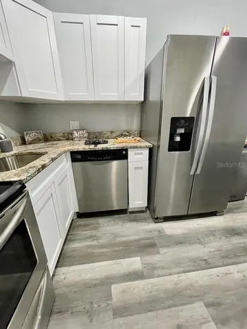 a kitchen with stainless steel appliances granite countertop a stove a sink and a refrigerator