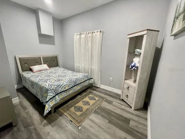 a bedroom with a bed rug and wooden floor