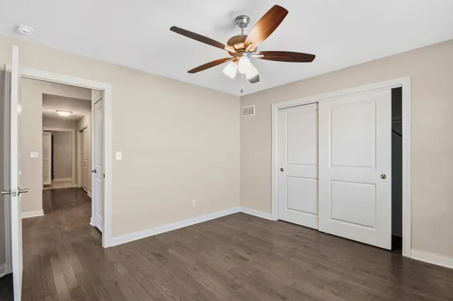 an empty room with wooden floor fan and windows