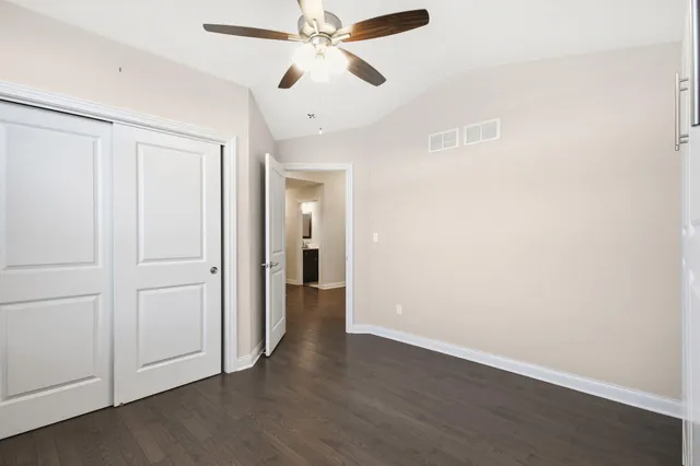 an empty room with wooden floor ceiling fan and windows
