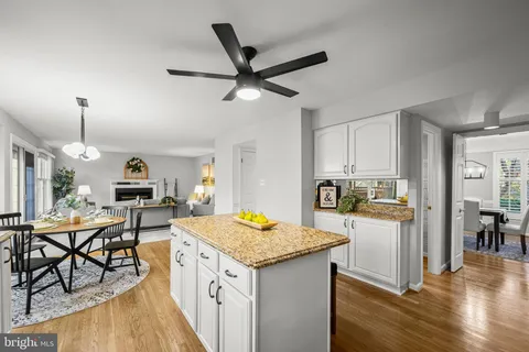 a kitchen with granite countertop kitchen island stainless steel appliances a stove a sink a dining table and chairs with wooden floor