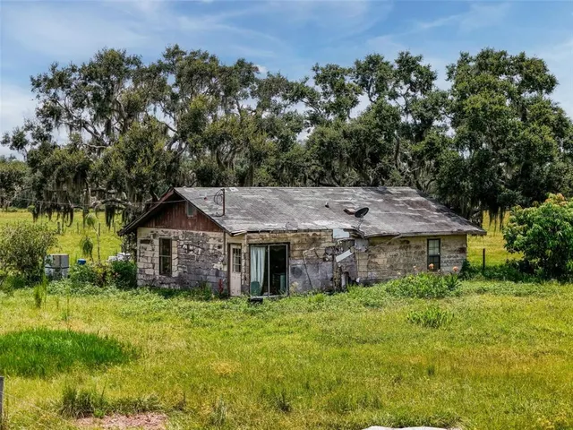 a view of a house with a big yard plants and large trees