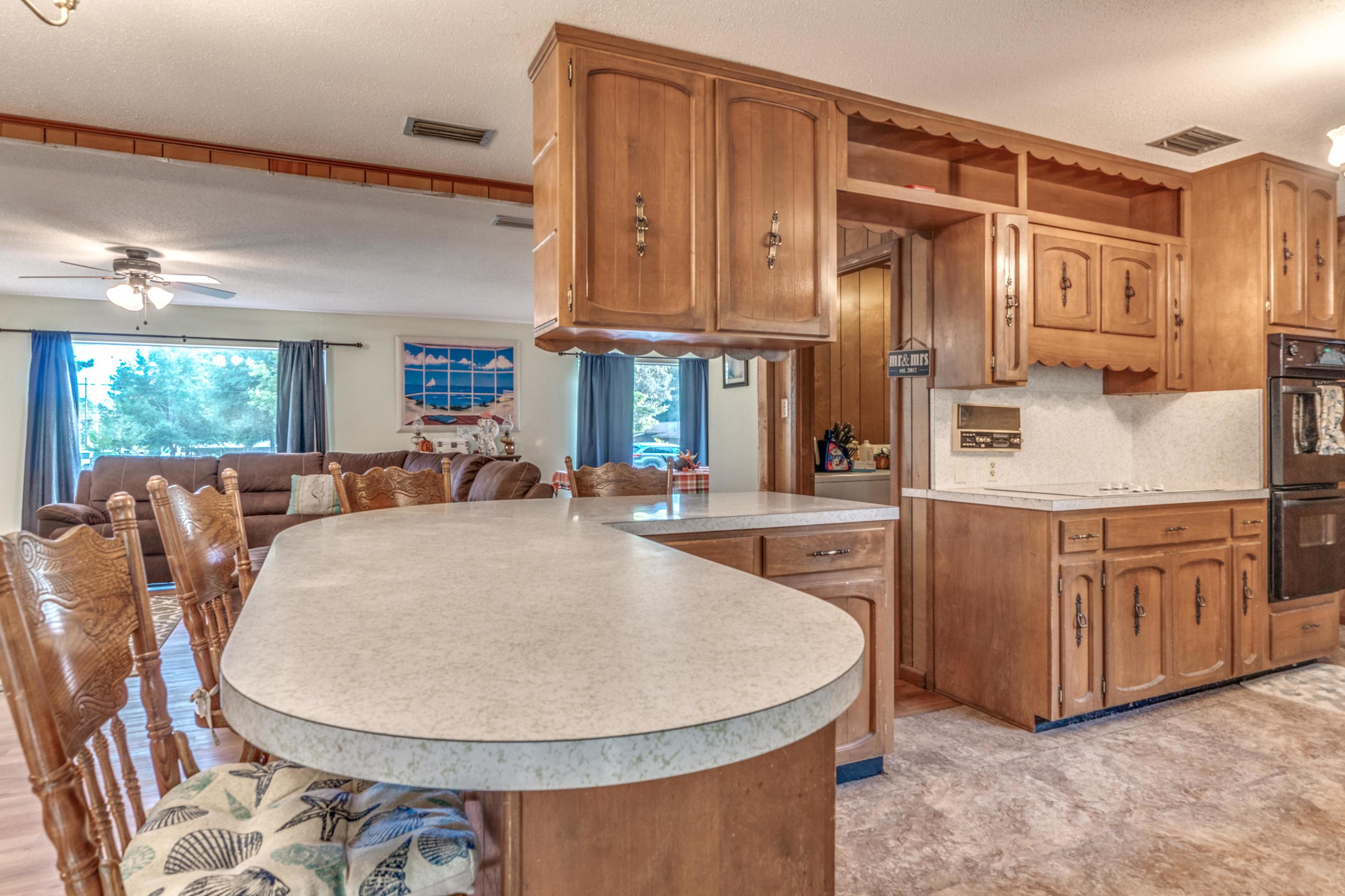 837 Cardinal Street Fort Walton Beach, FL 32547 - Photo 11 of 24 a living room with stainless steel appliances granite countertop a sink a microwave a dining table and chairs with wooden floor