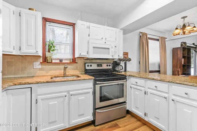 a kitchen with granite countertop white cabinets and white appliances