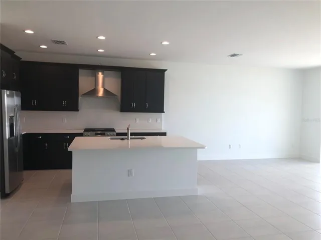 a large kitchen with stainless steel appliances a large counter top a stove and a sink