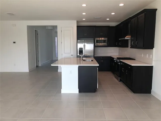 a kitchen with stainless steel appliances granite countertop a sink a stove and a refrigerator