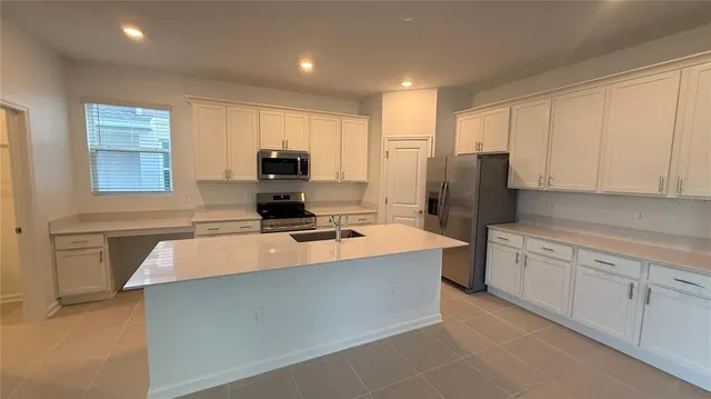 a large kitchen with stainless steel appliances granite countertop a stove a sink a refrigerator and a granite counter tops with white cabinets