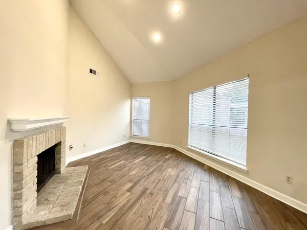 an empty room with wooden floor and a fireplace
