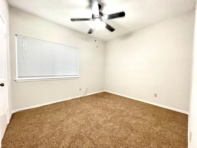 an empty room with a ceiling fan and a window