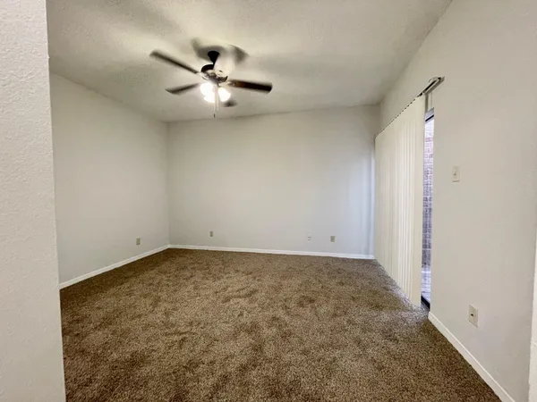 an empty room with a ceiling fan and carpet