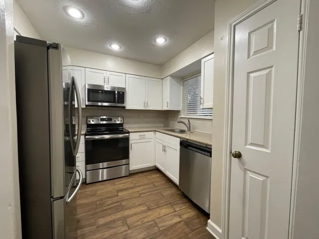 a kitchen with stainless steel appliances white cabinets and wooden floor