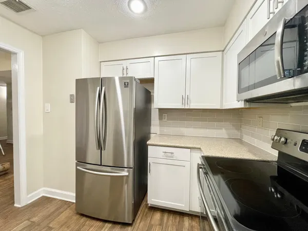 a kitchen with stainless steel appliances a refrigerator a sink and white cabinets