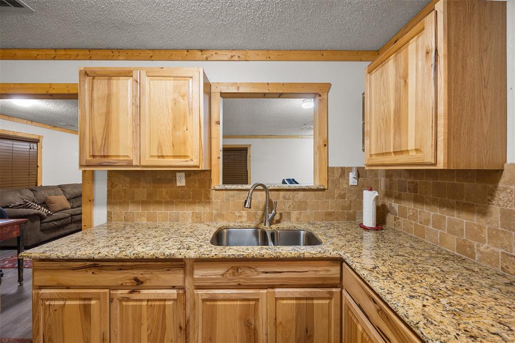 153 Center Loop Whitney, TX 76692 - Photo 3 of 21 a kitchen with granite countertop a sink a stove and cabinets