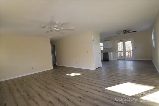 a view of an empty room with window and wooden floor