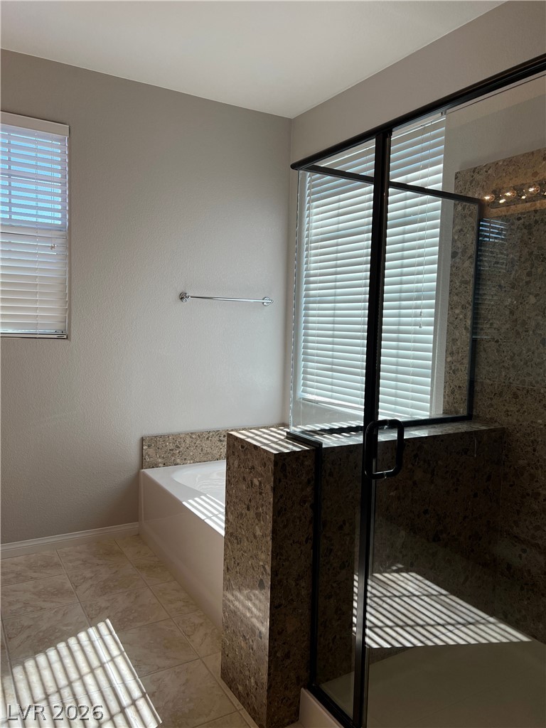 5981 Honeysuckle Ridge Street Las Vegas, NV 89148 - Photo 11 of 29 A well-lit bathroom featuring a large soaking tub and a spacious walk-in shower with sleek black framing.