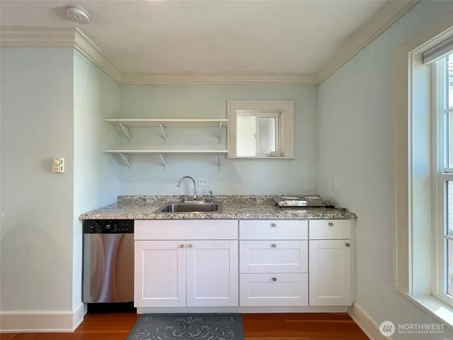 a kitchen with granite countertop a sink cabinets and stainless steel appliances