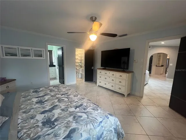 a spacious bedroom with a bed and a flat screen tv