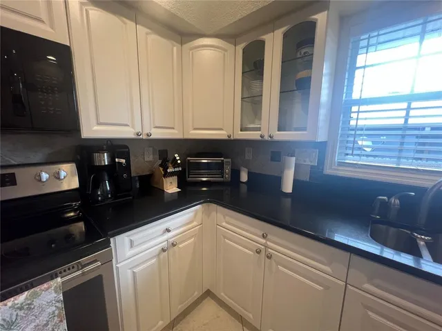a kitchen with granite countertop white cabinets and white appliances