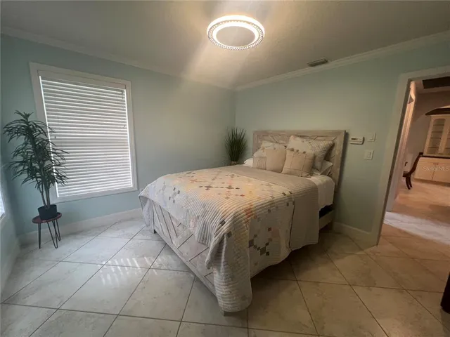 a bed sitting in a bedroom next to a window and chair