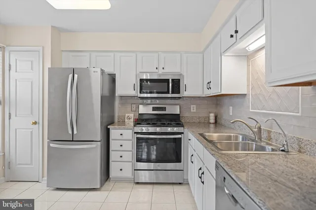 a kitchen with a granite countertop white cabinets and stainless steel appliances