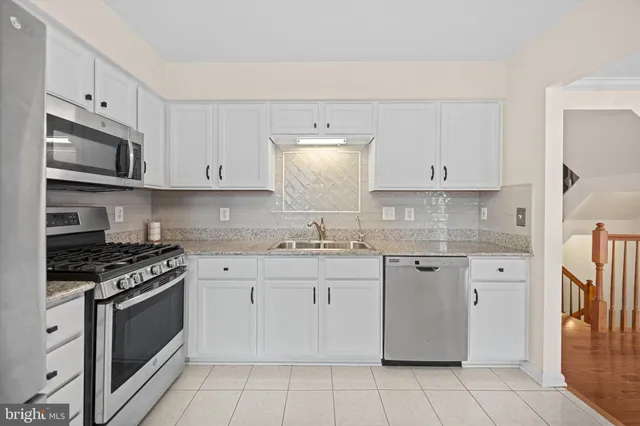 a kitchen with granite countertop white cabinets and appliances