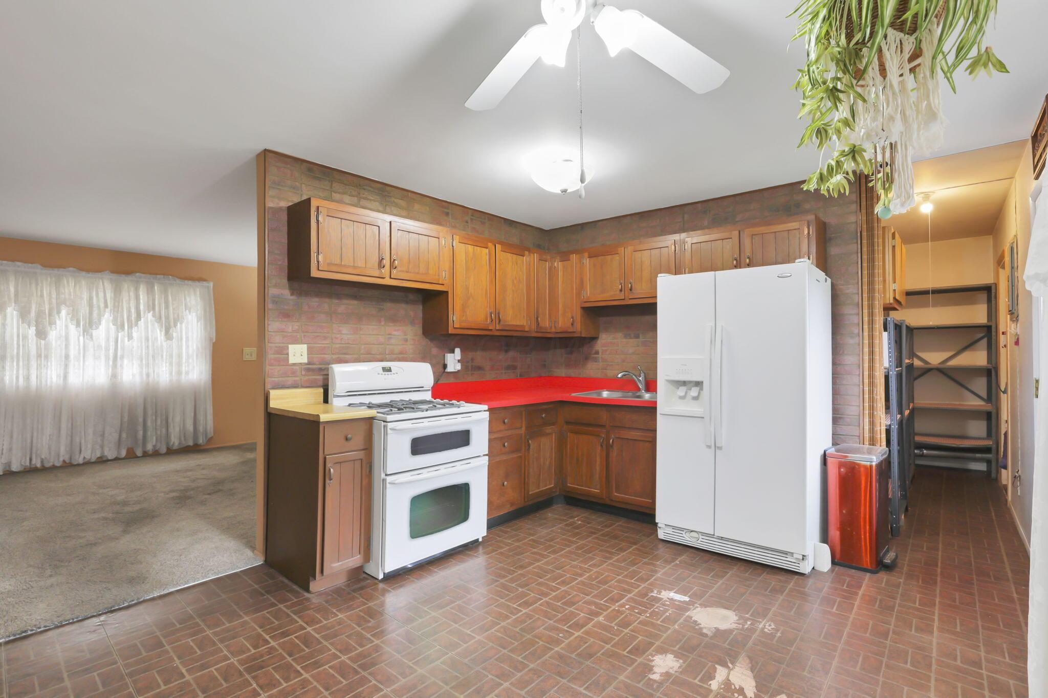 3882 Glenfield Road Columbus, OH 43232 - Photo 11 of 29 Functional kitchen with wood-finish cabinetry, red countertops, and tiled flooring